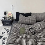 Black and white checkered bedding set on a bed with a nightstand and decor items.