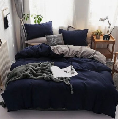 Navy blue bedding set on a bed in a bedroom with a side table and decor.